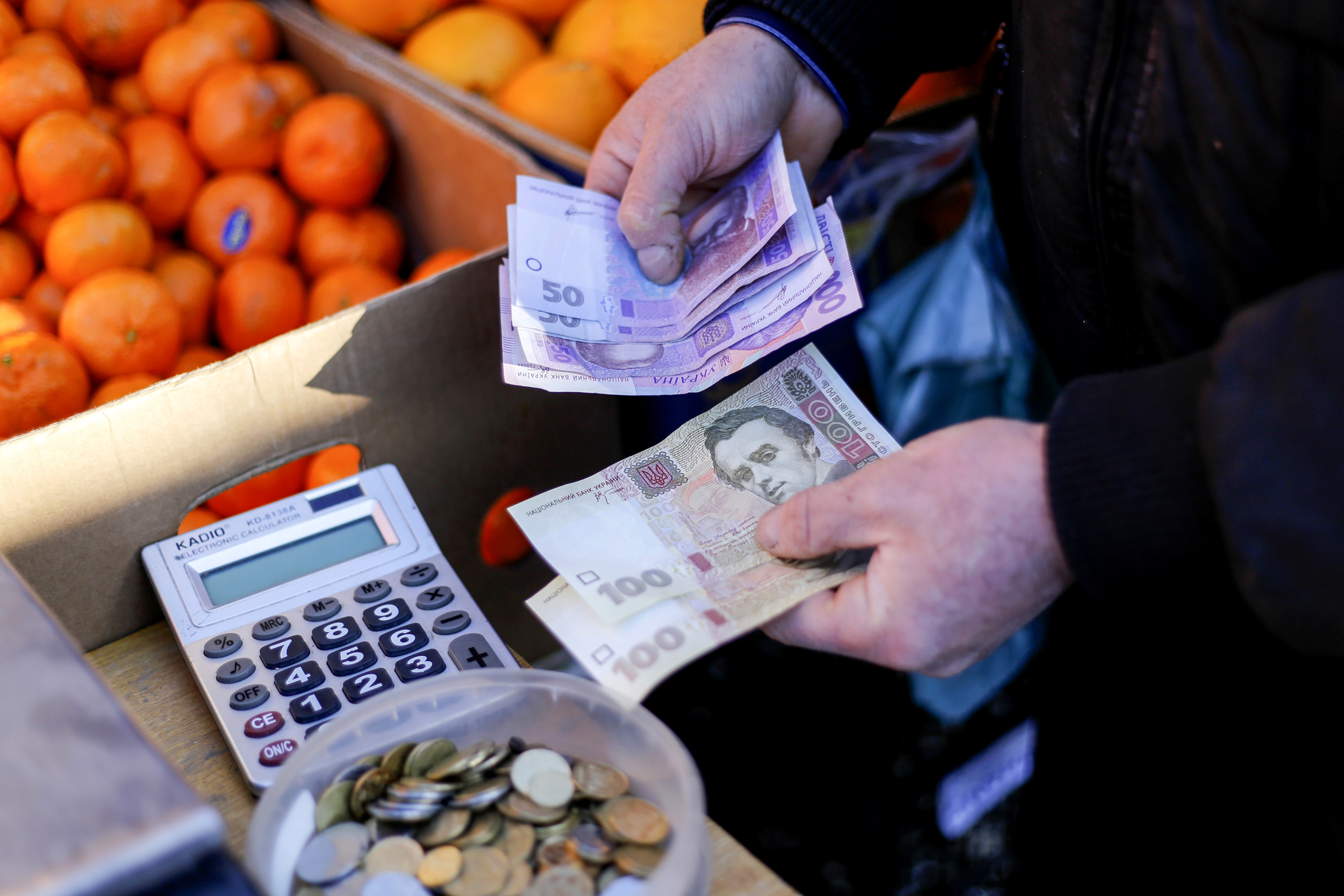 A market trader counts out hryvnia currency banknotes at a fruit stall in Kiev, Ukraine, on Monday, Feb. 3, 2014. Ukraine's opposition got a boost in its struggle to wrest power from President Viktor Yanukovych as a report said the European Union and U.S. are working on an aid package to rival assistance from Russia. Photographer: Vincent Mundy/Bloomberg